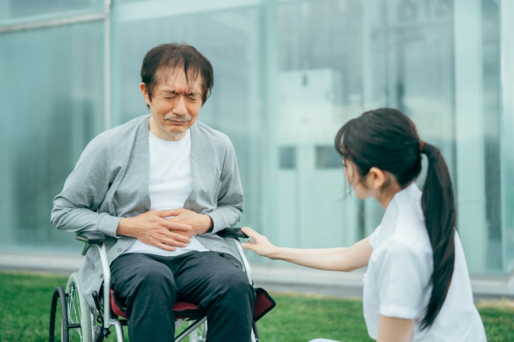 腹痛の男性と医療スタッフ